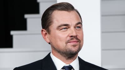 Leonardo DiCaprio i mörk kostym och vit skjorta tittar åt sidan och höjer något på ögonbrynen.