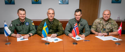 De nordiska flygvapencheferna sitter på rad vid ett bord framför sina flaggor. Alla klädda i militäruniform.