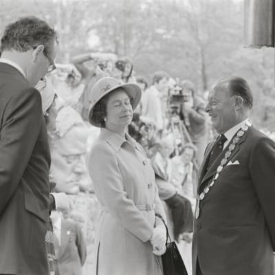 Englannin kuningatar Elisabet II vierailulla Sibeliuksen puistossa. Vasemmalla  tunnistamaton mies, keskellä kuningatar Elisabet (silmät kiinni) ja Helsingin  kaupunginjohtaja Teuvo Aura ja oikealla prinssi Philip (nauraa).