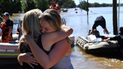 En mamma och dotter kramas då de återförenats efter att ha evakuerat undan översvämningar i Australien