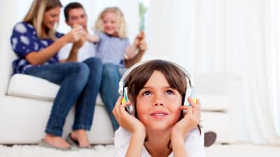 Pojke lyssnar med hörlurar i vardagsrum