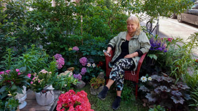 Margot Leinonen istuu taloyhtiön pihalle tekemässään puutarhassa Helsingin Punavuoressa.