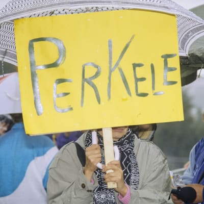 Työttömien mielenosoitus Helsingissä, marssijoita iskulauseineen ja banderolleineen eduskuntatalon edessä, henkilö pitelee kylttiä, jossa lukee "Perkele", 2. syyskuuta 1993.