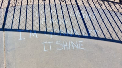 Text skriven med krita i gränsen mellan Mexiko och USA vid Friendship Park i Tijuana, "This little light of mine I am gonna let it shine".