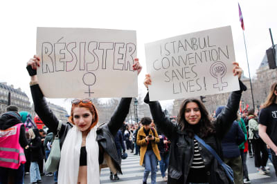 Två demonstranter i Paris håller skyltar med orden "Motstånd" och "Istanbulkonventionen räddar liv" 