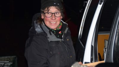 En kvinna i mössa och mörka kläder. Ute. Det är mörkt som mitt på natten. Oktober morgon kl 6.15.