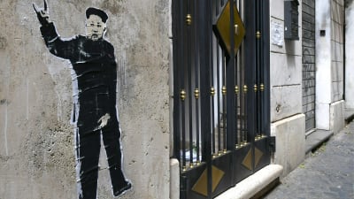 En satirisk väggmålning av Nordkoreas ledare Kim Jong-Un utanför en begravningsbyrå i rom
