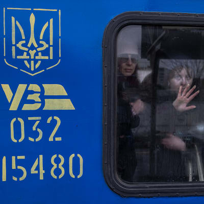 Evakuoitavia ihmisiä katsoo junan ikkunasta Kiovan juna-asemalla.