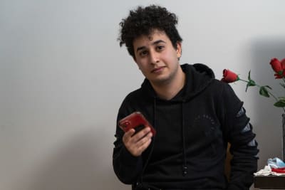 Zein al-Battat sitter med sin telefon i handen bredvid en vas med rosor.