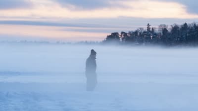 En gammal man går på isen i dimma.
