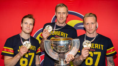 Mikko Lehtonen, Marko Anttila och Veli-Matti Savinainen visar upp VM-pokalen och sina guldmedaljer.