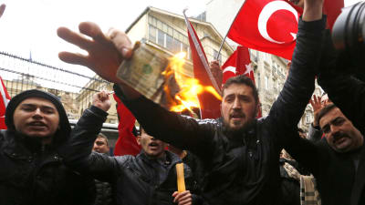 Anhängare av president Recep Tayyip Erdoğan brände upp en amerikansk dollar och skrek slagord mot Nederländerna utanför det holländska konsulatet i Istanbul den 12 mars 2017.