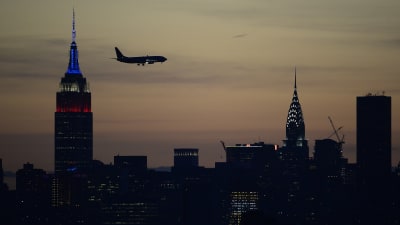 New Yorks och ett flygplans siluett mot solnedgången.