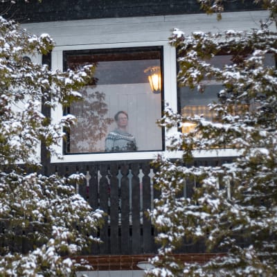 Kuvassa Kirsi Vuorela, katsoo kotinsa ikkunasta ulos. 