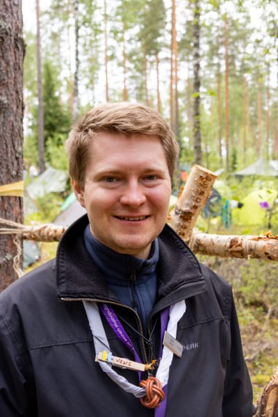 En man i blå rock står i skogen