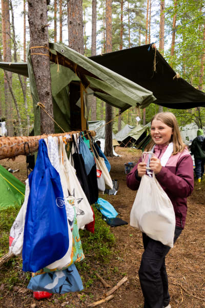 En flicka i ljusröd rock med en tygkasse i handen