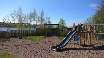 Lekplats med rutschbana. I bakgrunden skymtar havet.