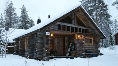 Snötäckt timmerstuga på Levi i Kittilä i Lappland. 