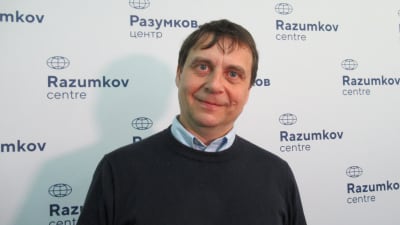 Forskaren Viktor Zimjatin poserar för kameran framför ett plakat med texten Razumov centre.