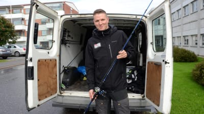 Jani Haavisto framför sin bil med ett fiskespö.