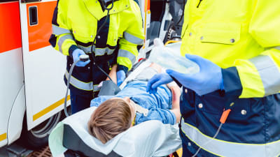 Ambulanspersonal hjälper skadad pojke