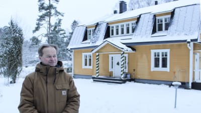 niklas tevajärvi framför sitt hus, en gul villa.