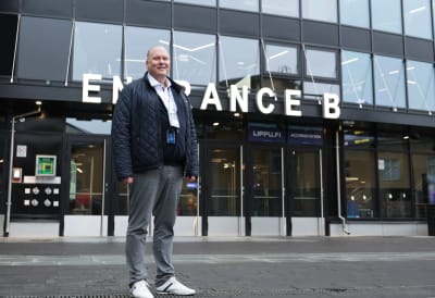 Nokia Arenan toimitusjohtaja Marko Hurme seisoo Nokai Arenan ovien edustalla, katsoo hymyillen kameraan päällään musta takki.