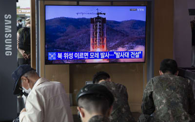 På en bildskärm syns en raketavfyrning, militärklädda personer följer med det som sker i bild.