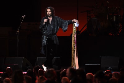 Russel Brand lavalla puhumassa mikrofoniin.