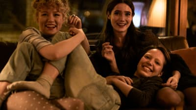 Tre skrattande flickor i en soffa.