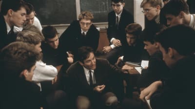 Scen ur filmen "Döda poeters sällskap". Robin Williams sitter omringad av pojkarna i hans klass. 