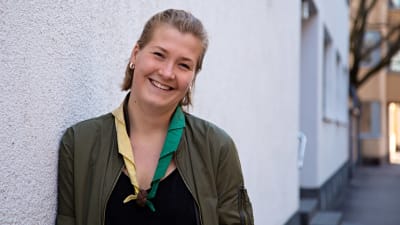 En ung kvinna med scouthalsduk ler och tittar in i kameran.