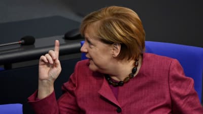 Angela Merkel tittar åt sidan och håller upp ett finger