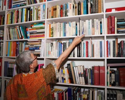 Nainen osoittaa kirjahyllyssä olevaa kirjaa.