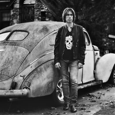 Per Gessle fotograferad framför gammal amerikansk bil.