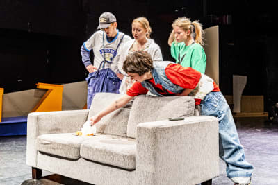En grupp unga skådespelare vid en soffa.