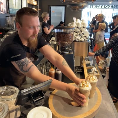 Kokkolan Espresso Housen työntekijä ojentaa kaksi take away -kahvia tiskille.