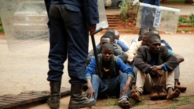 Kravallpolis ståd framför gripna demonstranter i Zimbabwes huvudstad Harare