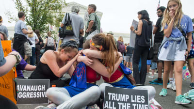 Sörjande demonstrerande flickor kramar om varandra utanför Högsta domstolen i Washington DC