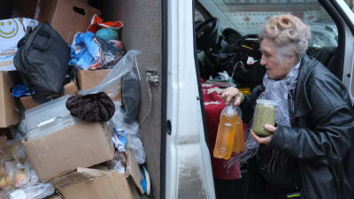 En äldre dam lastar in matvaror i skåpbil
