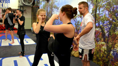 Två kvinnor tränar thaiboxning inne i en träningslokal.