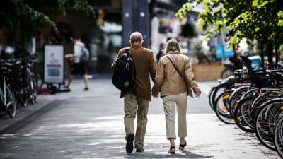 Ett medelålders par går hand i hand mitt på en gata i Helsingfors.