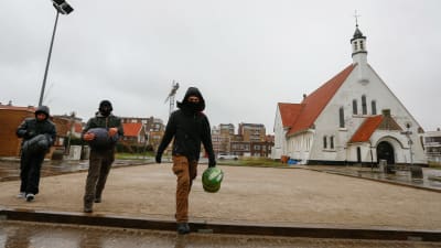 Tre migranter utanför kyrkan i Zeebrugge. 