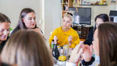 Ulrikke Falch med andra tjejer runt ett bord. 