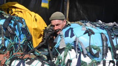 En soldat står i skydd bakom en blå-gul barrikad.