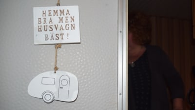 En skylt hänger på en husvagnsdörr där det står "Hemma bra men husvagn bäst".
