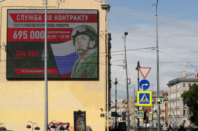 Rakennuksen seinässä oleva mainostaulu, jossa on sotilaan kuva ja sotilasuraa mainostava teksti.