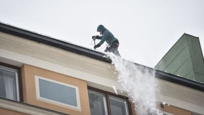 En snöskottare på ett tak i Berghäll i Helsingfors tisdagen den 29.1.2019.
