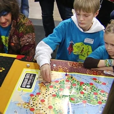 Lapsia ja aikuisia pöydälle levitetyn Afrikan tähti -pelin ympärillä.