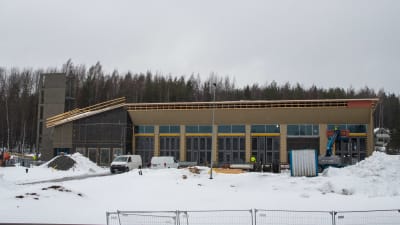 En brandstation under uppbyggnad. Bilar och redskap står utanför ena långsidans stora fönster.